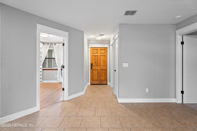 tiled empty room with a textured ceiling