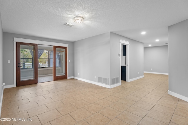 tiled empty room featuring french doors and a textured ceiling