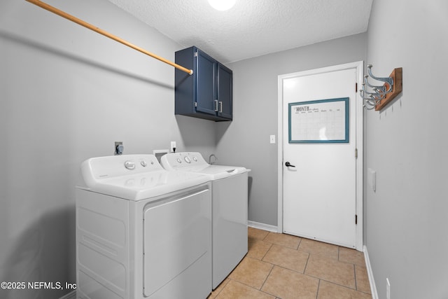 laundry room featuring a textured ceiling, cabinets, washer and dryer, and light tile patterned floors