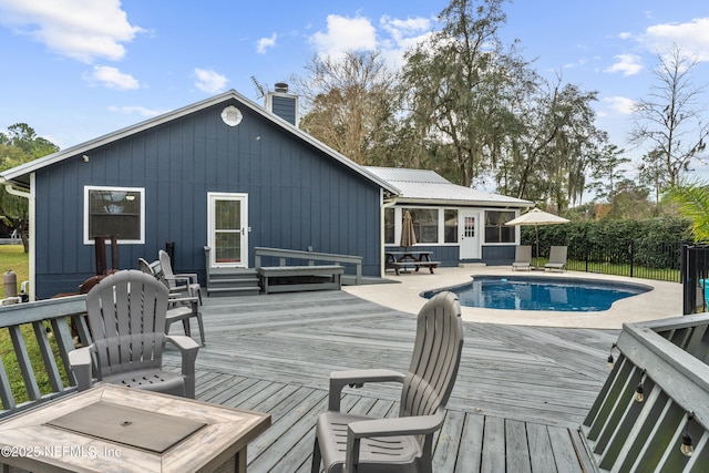 rear view of property featuring a swimming pool side deck and a sunroom