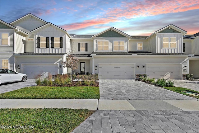 townhome / multi-family property featuring a garage and a lawn