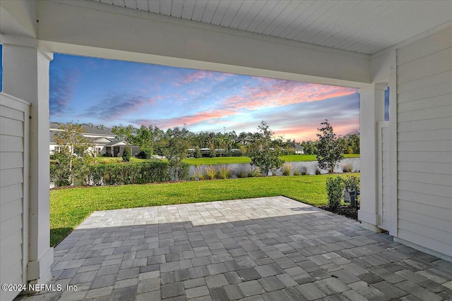 patio terrace at dusk featuring a lawn