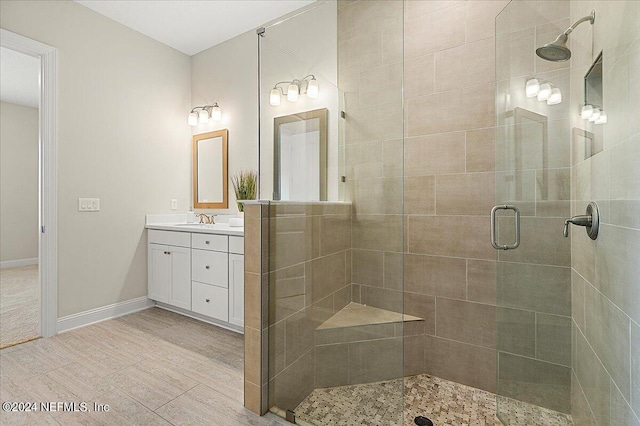 bathroom featuring a shower with door and vanity