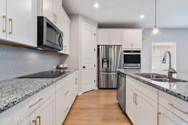 kitchen with light stone countertops, appliances with stainless steel finishes, sink, decorative light fixtures, and white cabinetry