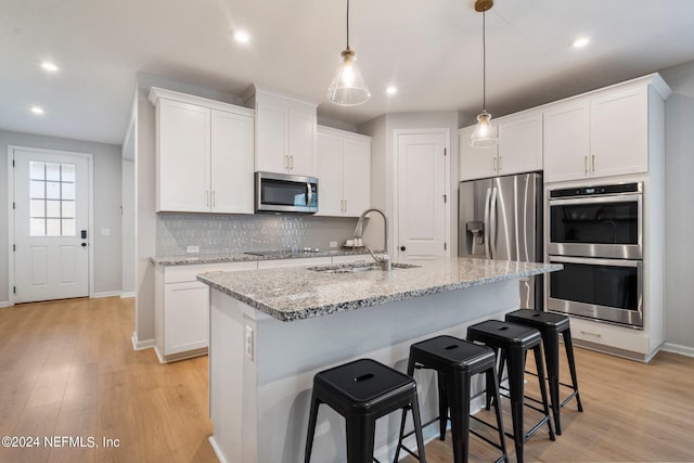 kitchen with white cabinets, stainless steel appliances, and an island with sink