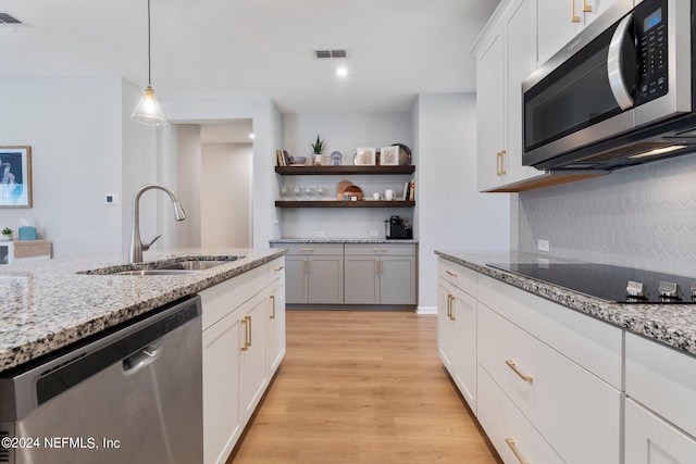 kitchen featuring sink, hanging light fixtures, light hardwood / wood-style floors, white cabinetry, and stainless steel appliances