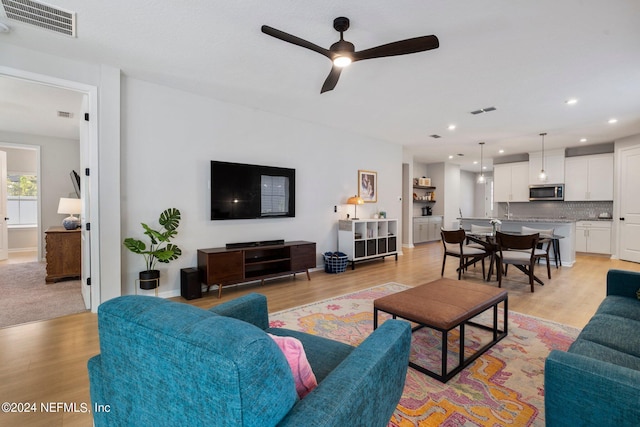 living room with ceiling fan and light hardwood / wood-style floors