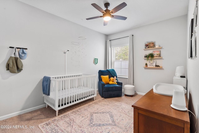 bedroom featuring a nursery area and ceiling fan