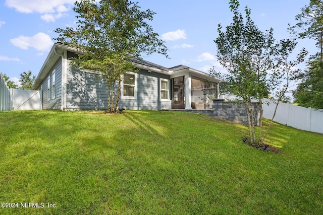 back of property featuring a sunroom and a lawn