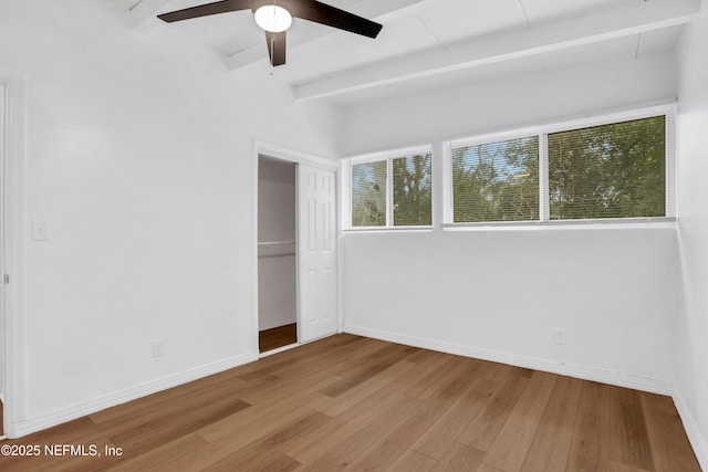 unfurnished bedroom featuring ceiling fan, a closet, beamed ceiling, and wood-type flooring