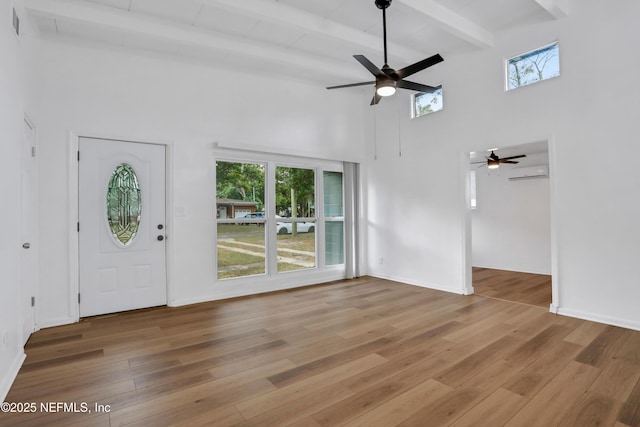 entryway featuring beam ceiling, hardwood / wood-style flooring, a wall unit AC, and ceiling fan