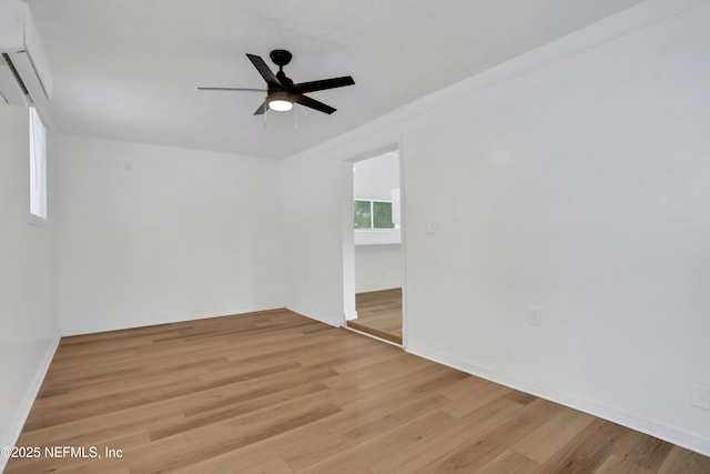 empty room featuring ceiling fan, light wood-type flooring, crown molding, and a wall unit AC