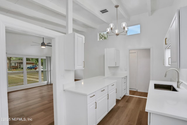 kitchen featuring white cabinets, ceiling fan with notable chandelier, sink, beamed ceiling, and decorative light fixtures