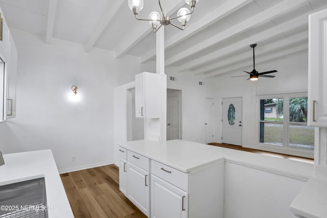 kitchen with ceiling fan with notable chandelier, beam ceiling, pendant lighting, white cabinets, and light hardwood / wood-style floors