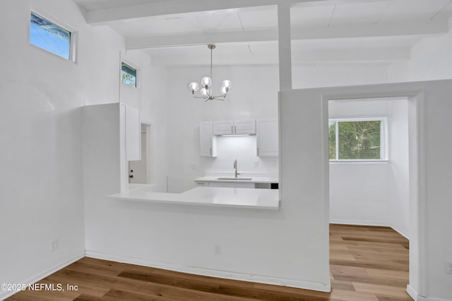 kitchen with an inviting chandelier, sink, hanging light fixtures, light wood-type flooring, and white cabinetry