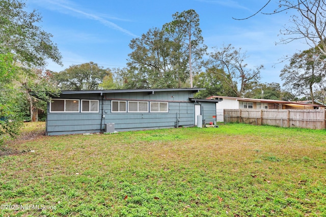 back of property with central AC and a lawn