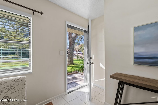 entrance foyer featuring a textured ceiling, light tile patterned floors, and a healthy amount of sunlight