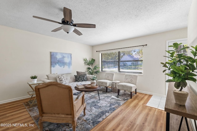 living room with a textured ceiling, ceiling fan, and hardwood / wood-style floors