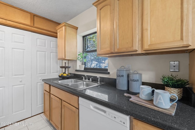 kitchen with a textured ceiling, dishwasher, sink, light tile patterned flooring, and light brown cabinets