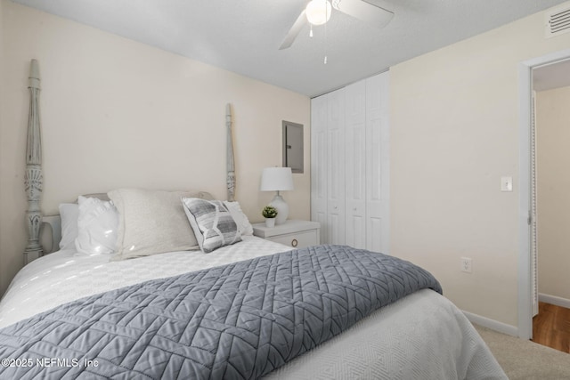 carpeted bedroom featuring electric panel, ceiling fan, and a closet