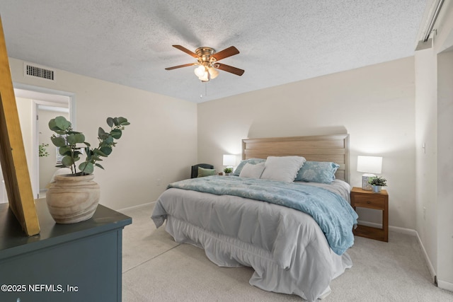 bedroom featuring ceiling fan, light carpet, and a textured ceiling