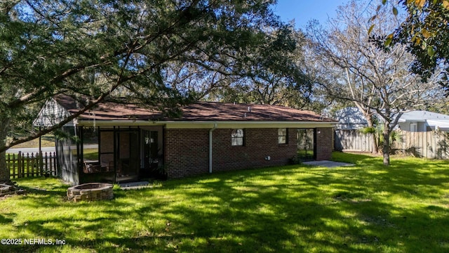 back of property featuring an outdoor fire pit and a lawn