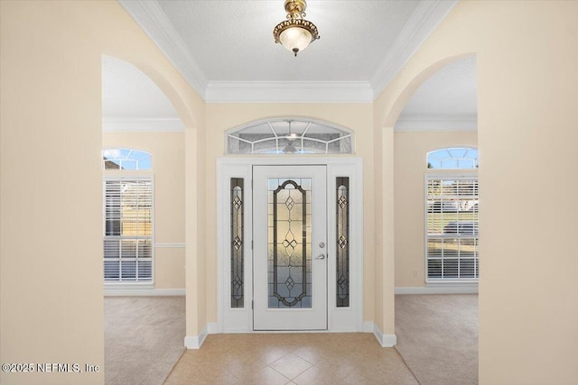 carpeted foyer entrance with a wealth of natural light, crown molding, and a textured ceiling