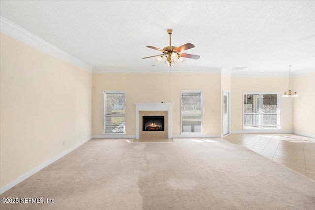 unfurnished living room with ceiling fan with notable chandelier, light colored carpet, a wealth of natural light, and crown molding