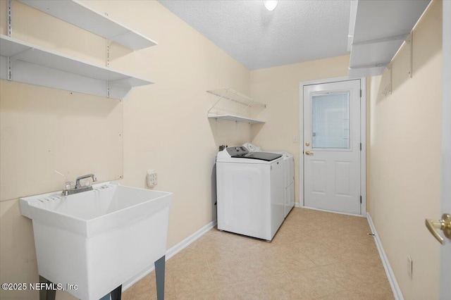 washroom with washer / dryer, a textured ceiling, and sink