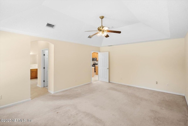 carpeted spare room with a tray ceiling, ceiling fan, and vaulted ceiling