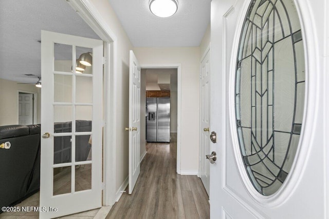 interior space featuring ceiling fan, french doors, light hardwood / wood-style floors, and a textured ceiling