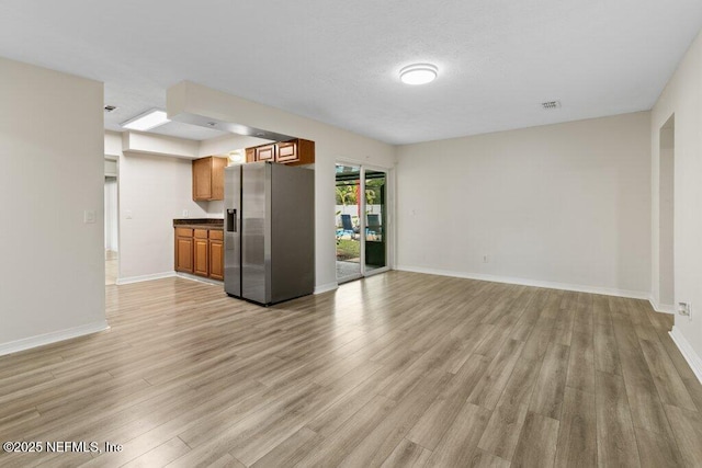 interior space with stainless steel refrigerator with ice dispenser and light wood-type flooring