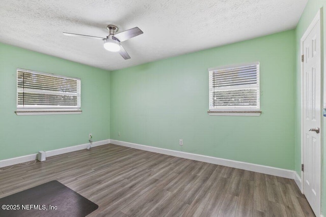 empty room with ceiling fan, wood-type flooring, and a textured ceiling