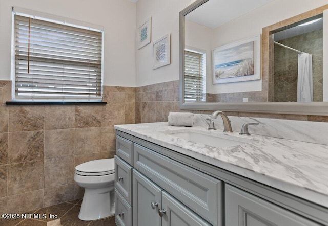 bathroom with tile patterned flooring, vanity, toilet, and tile walls