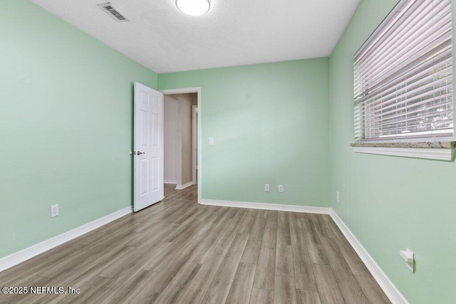 spare room featuring a textured ceiling and light wood-type flooring