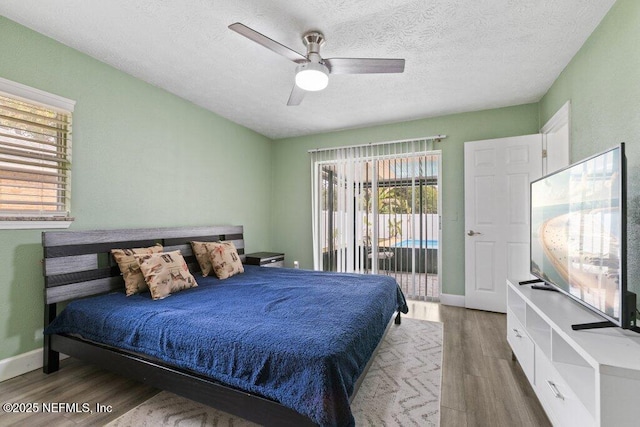 bedroom with access to exterior, ceiling fan, hardwood / wood-style floors, and a textured ceiling