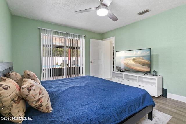 bedroom featuring access to exterior, a textured ceiling, light hardwood / wood-style floors, and ceiling fan