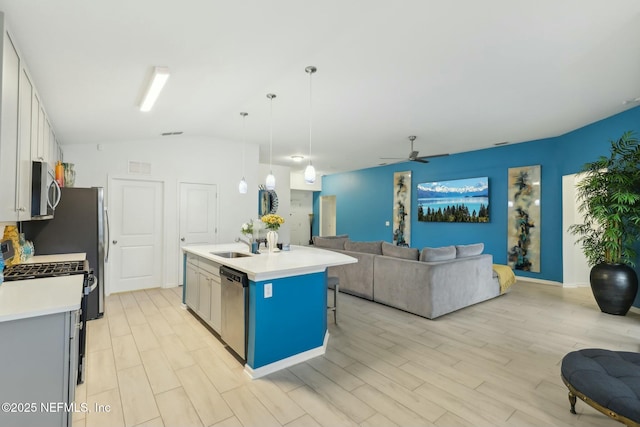 kitchen featuring ceiling fan, stainless steel appliances, decorative light fixtures, a kitchen island with sink, and white cabinets