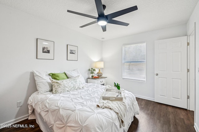 bedroom featuring dark hardwood / wood-style flooring, ceiling fan, and a textured ceiling