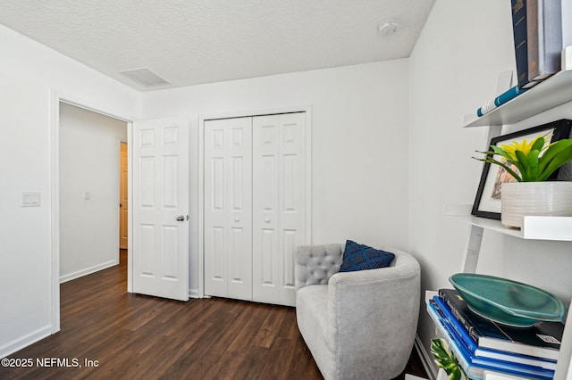 living area with a textured ceiling and dark hardwood / wood-style flooring