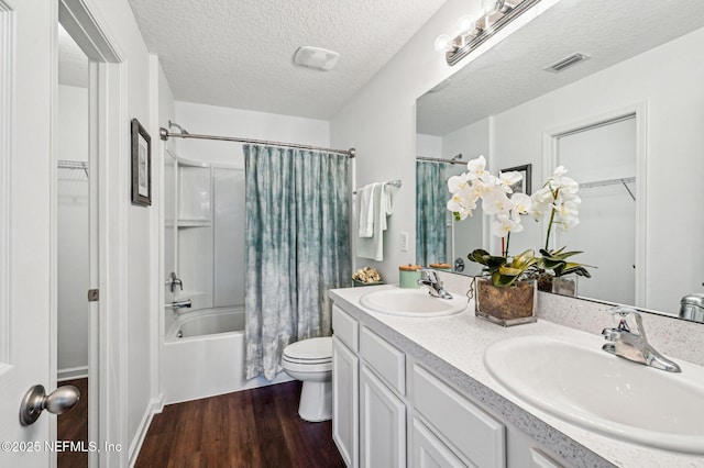 full bathroom with toilet, shower / tub combo, a textured ceiling, vanity, and hardwood / wood-style floors