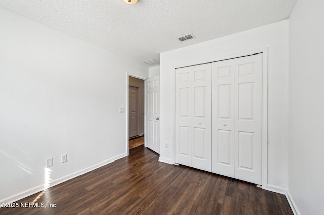 unfurnished bedroom featuring a closet, dark hardwood / wood-style floors, and a textured ceiling