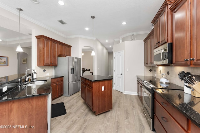 kitchen with sink, hanging light fixtures, light hardwood / wood-style flooring, appliances with stainless steel finishes, and tasteful backsplash