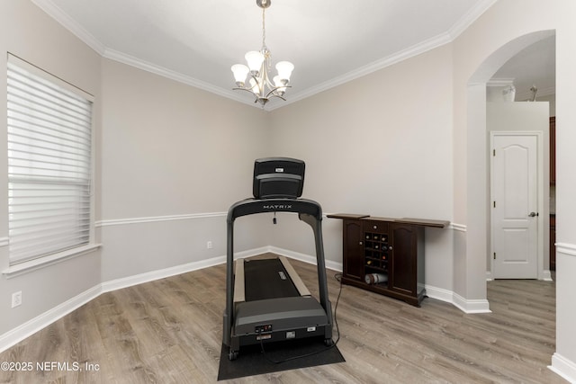 workout room featuring light hardwood / wood-style flooring, a chandelier, and ornamental molding