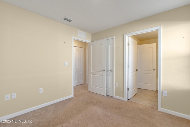 unfurnished bedroom featuring ensuite bathroom and light colored carpet