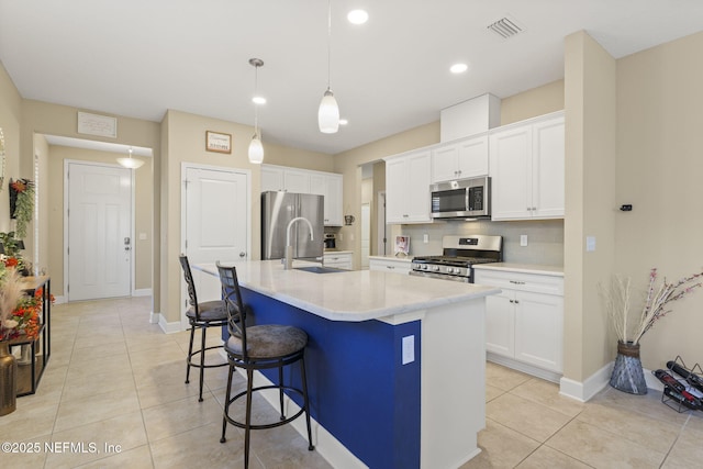 kitchen with pendant lighting, white cabinetry, an island with sink, a kitchen breakfast bar, and stainless steel appliances