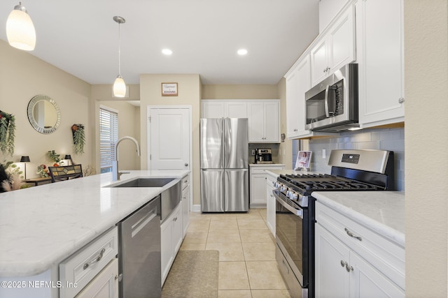 kitchen with white cabinetry, tasteful backsplash, decorative light fixtures, stainless steel appliances, and a kitchen island with sink