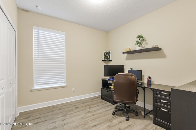 home office with light hardwood / wood-style floors and a textured ceiling