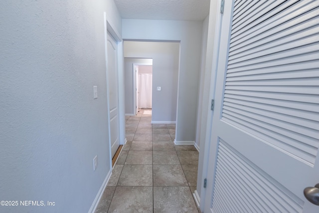 hallway featuring light tile patterned floors and a textured ceiling