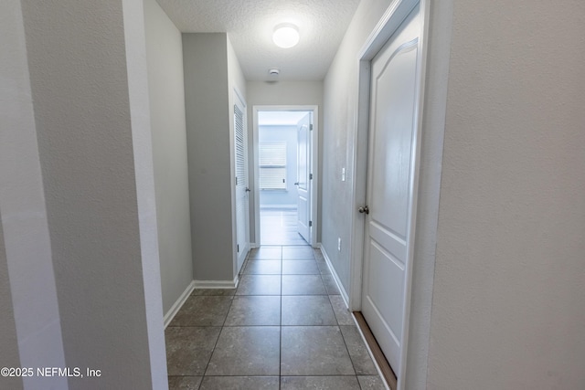 corridor featuring dark tile patterned flooring and a textured ceiling